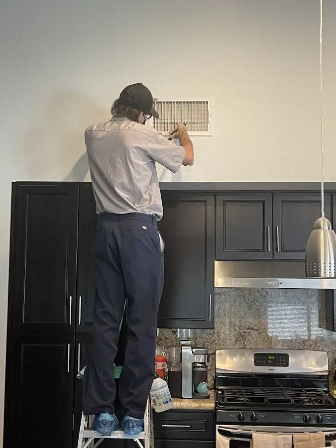 Technician inspecting an air vent during HVAC service in St. Paul